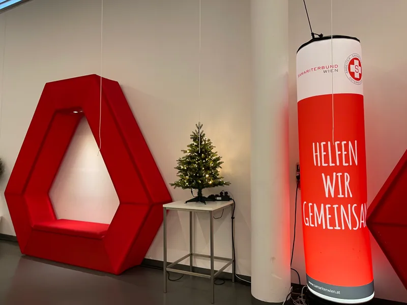 A seating area at the Austria Center with an illuminated Samariterbund sign and a small Christmas tree