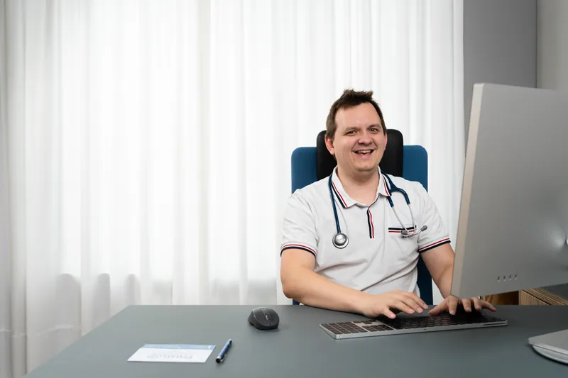 Helmut Steinbrecher laughing at his desk in his medical practice