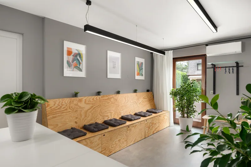 The waiting area at Praxis 23 with a wooden bench, cushions and plants